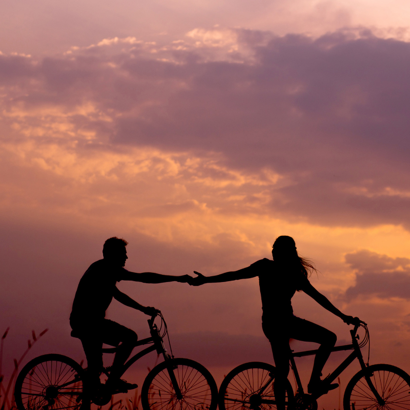 Couple holding hands whilst riding bicycles