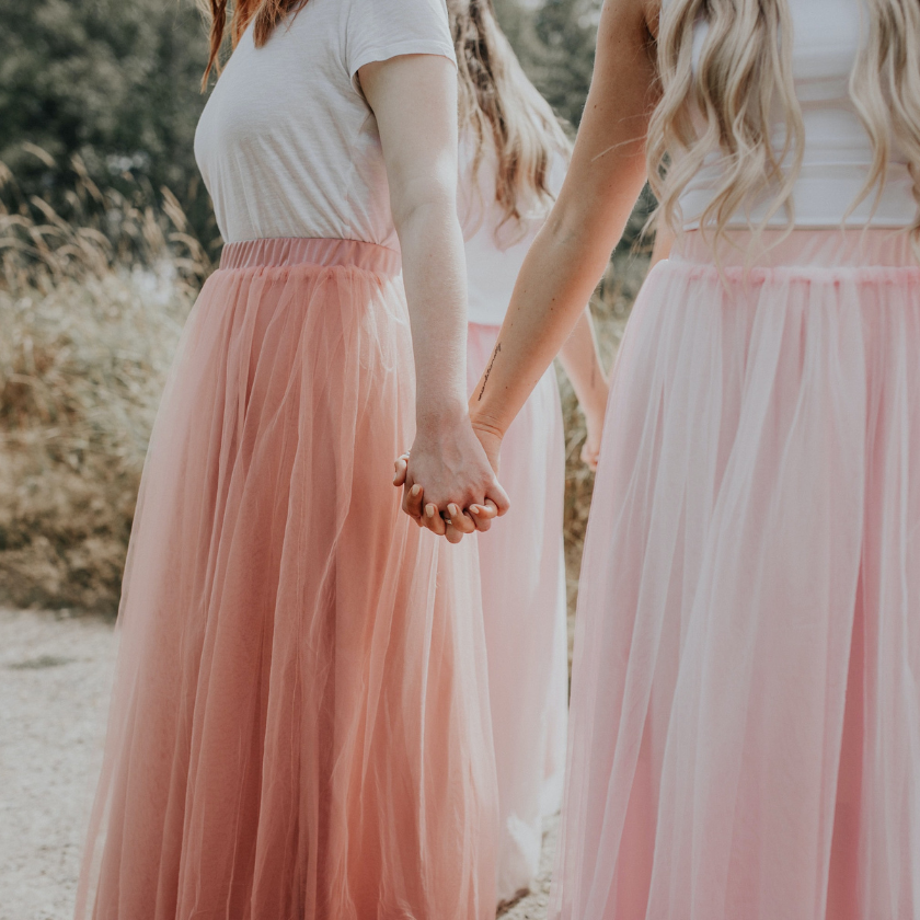 Group of women holding hands in bridesmaid dresses