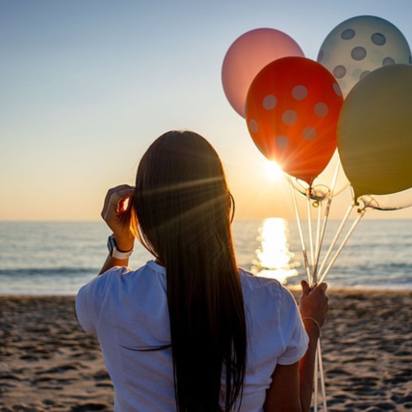 woman with balloons on a beach